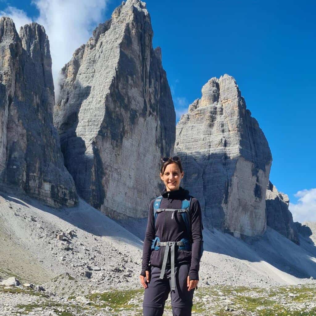 Eine Frau mit Rucksack vor drei großen Felsen.