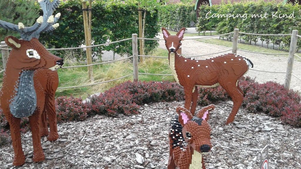 Drei Rehe aus Bausteinen stehen hinter einem Zaun.