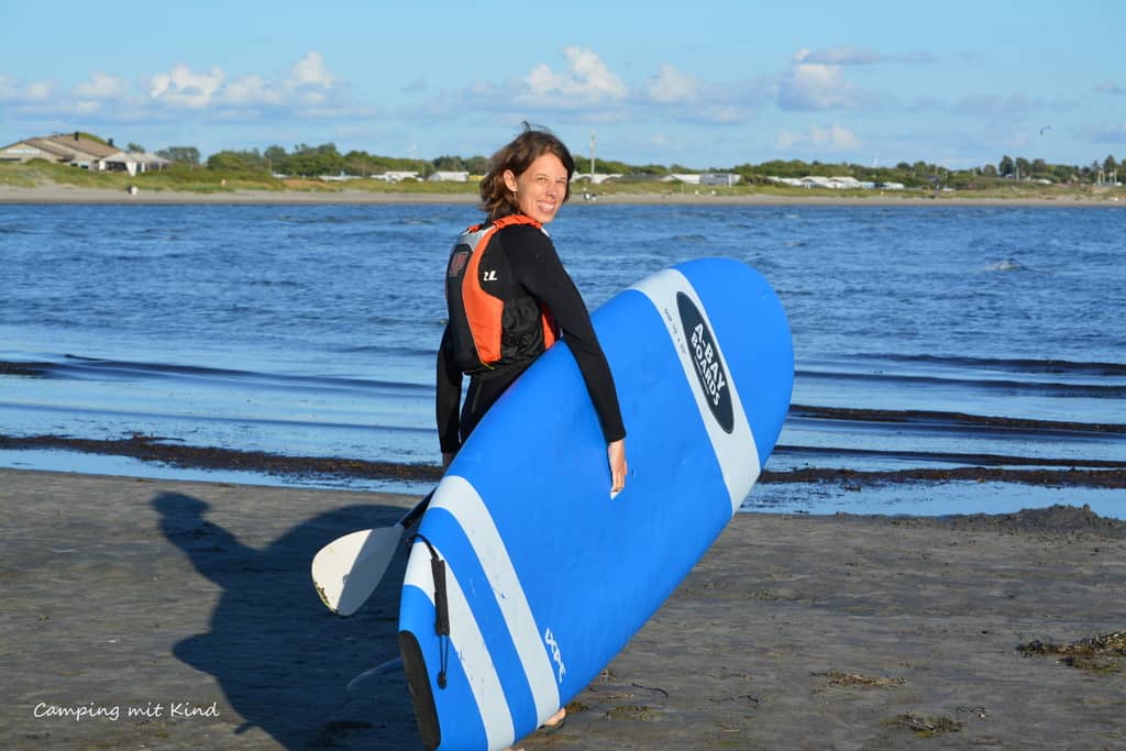 Eine Frau hält in der Hand ein Stand-Up_Paddleboard