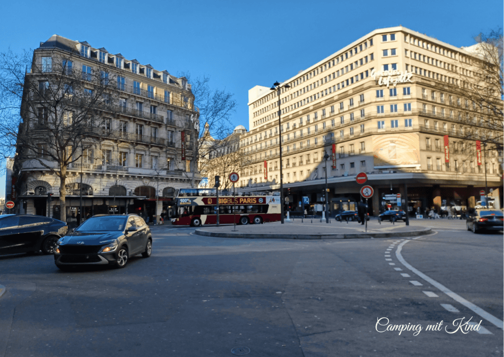 Zwei ältere Gebäude, davor befindet sich ein großer Bus mit der Aufschrift Paris