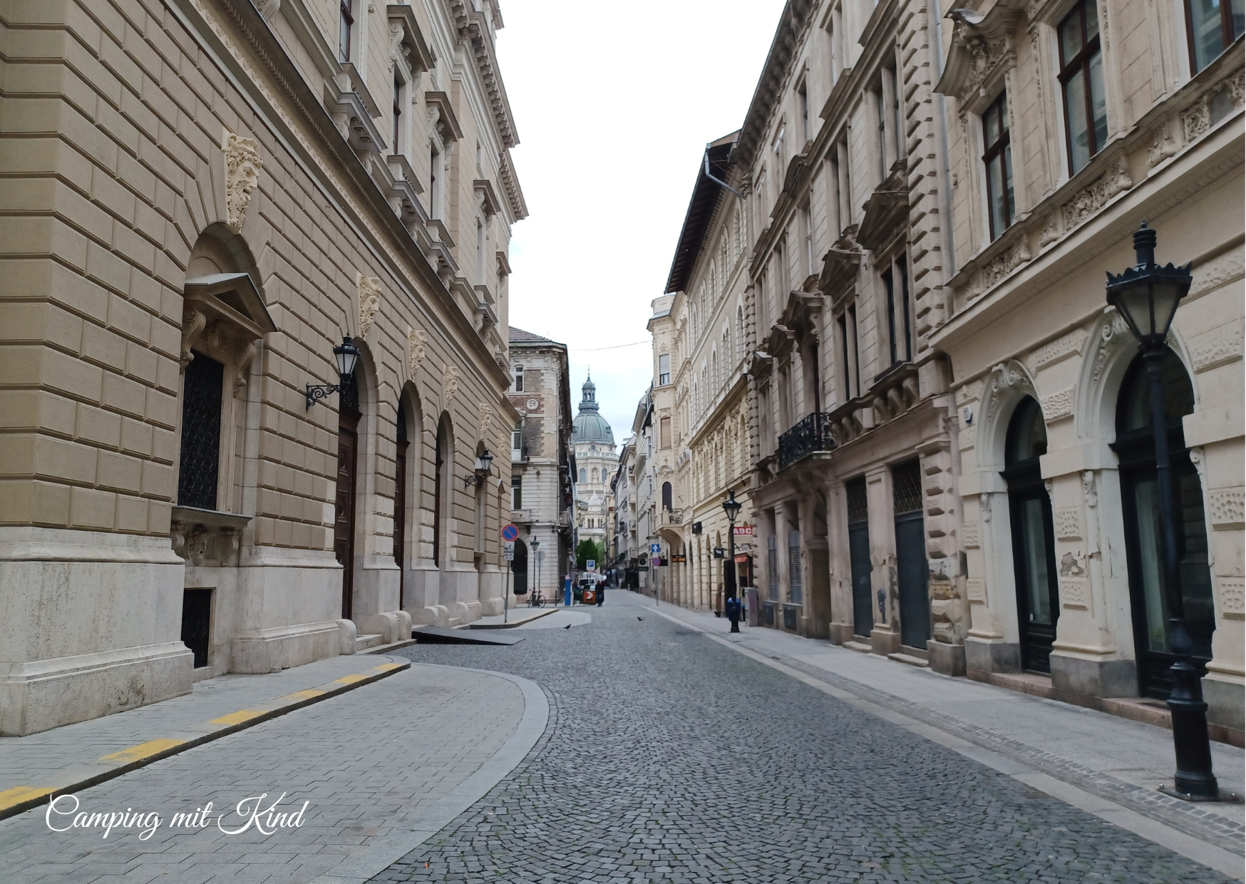 Links und rechts Häuserfronten, in der Mitte eine Straße mit Pflastersteinen