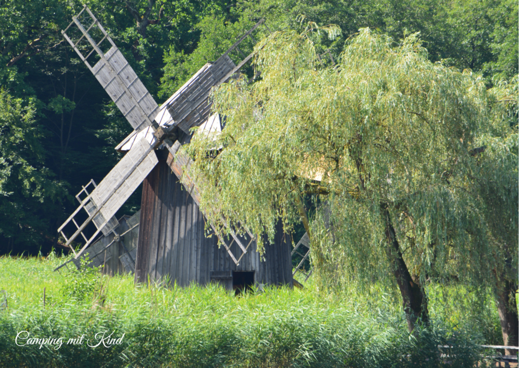 Eine Windmühle steht neben einem Baum