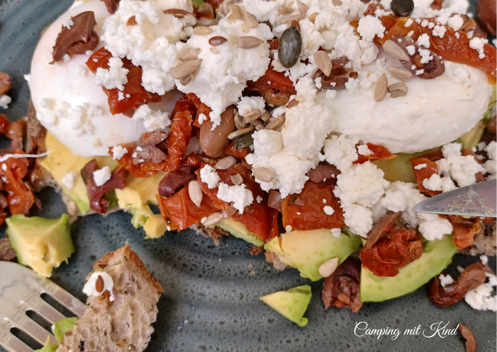 Ein Teller mit Brot, Avocado, Käse, getrocknete Tomaten und Ei.