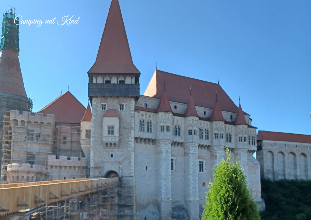 Eine alte Festung mit hohen Türmen. Davor befindet sich eine hölzerne Brücke.