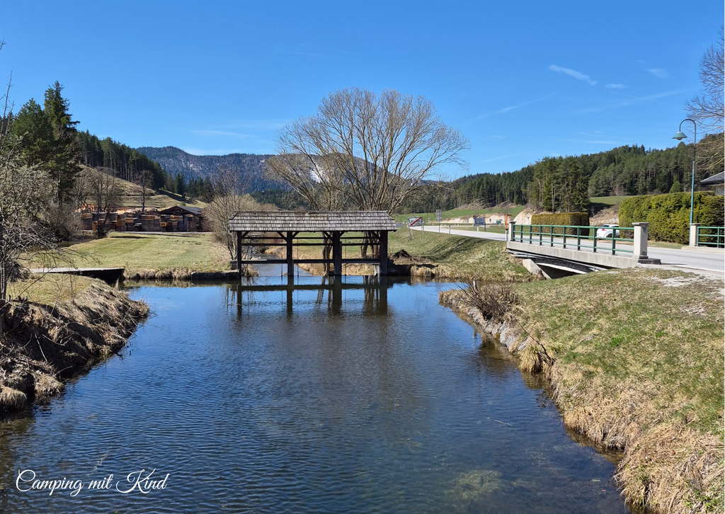 Wasser fließt. Daneben befinden sich Wiesen und eine Straße